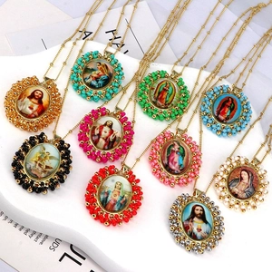 Close-up of religious oval pendants with colorful bohemian beads on thin gold chains