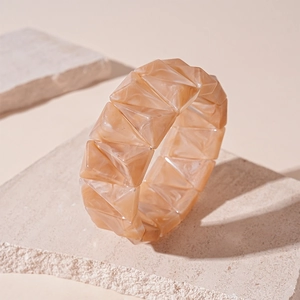 Detail of warm orange marble resin bracelet showing geometric triangular prism structure