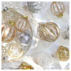 Close-up of sparkling gold and silver Christmas ornaments with sequins on white tray