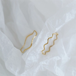 Close-up of minimalist gold plated wavy rings with geometric zig-zag and thin ripple patterns
