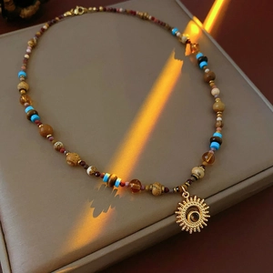 Macro detail of sun pendant beaded necklace with natural stones on beige display