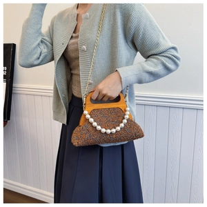 Retro tweed handbag detail with wooden handle, pearl accent, and gold chain strap