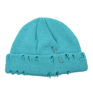 Macro shot of bright blue distressed knit beanie with safety pin and ring metal details