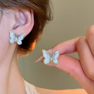 Detailed view of silver butterfly stud earrings with iridescent shell texture and crystal inlay