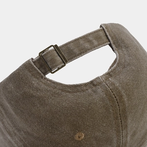 Detail of cotton baseball cap with adjustable bronze metal buckle and washed fabric texture