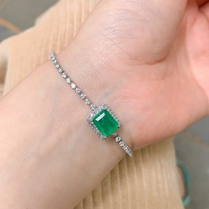 Detailed view of rectangle green gemstone bracelet with small diamonds on wrist