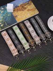 Close-up of assorted woven handbag straps with gold metal hardware on a textured desk