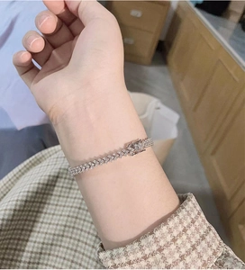 Close-up of a silver moissanite tennis bracelet with micro-pave setting on a wrist