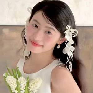 Detail of elegant shell bow earrings and pearl pendants on a female model with flowers