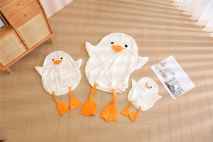 Detailed view of three various sizes of cute white duck plush toy shells on wood floor