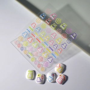 Detailed macro of 5D embossed bear nail stickers and floral patterns for DIY manicures