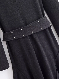 Detailed close-up of dark grey denim dress waist with silver metal studs belt decoration