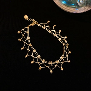 Close-up of golden multi-layer bracelet featuring lace mesh structure and cubic charms