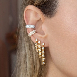 Close-up of gold and silver ear cuffs with long tassel earrings featuring clear diamonds