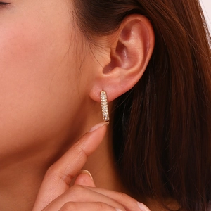 Detail of 18K gold plated rectangular earrings with inlaid diamonds on a model