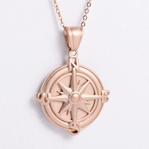 Macro shot of rose gold compass pendant with sandblasted finish and direction letters