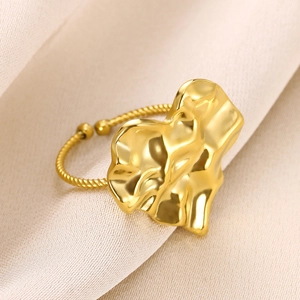 Close-up of golden heart ring with irregular texture and twisted open band on silk fabric