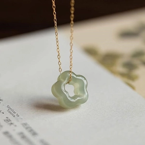 Detailed view of green jade flower pendant necklace on book background