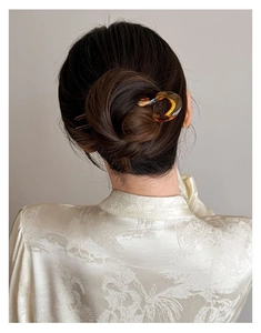 Detailed view of an amber U-shaped acrylic hair pin securing a high bun hairstyle