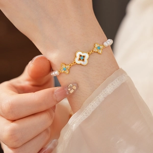 Dettaglio macro del bracciale di perle placcato oro 18k con ciondoli a quadrifoglio turchese