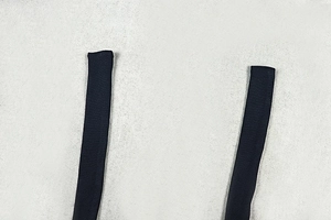Close-up of black backless dress strap showing detailed woven texture and fabric finish