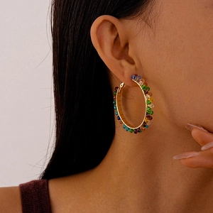Close-up of a model wearing colorful beaded hoop earrings with vibrant rainbow glass beads