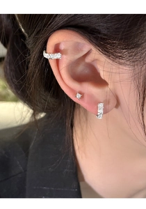 Macro detail of silver U-shaped earrings and star stud with shimmering cubic zirconia
