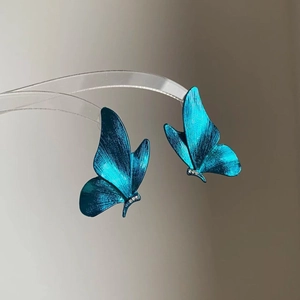 Gros plan détaillé de la boucle d'oreille papillon bleue avec métal brossé et cristaux
