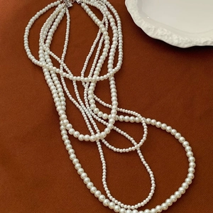 French vintage multi-layer pearl necklace with white round beads on a textured background