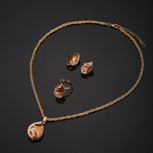 Close-up of gold jewelry set featuring amber stones and crystals on reflective surface
