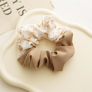 Detail of floral and herringbone fabric scrunchie on a decorative cream tray