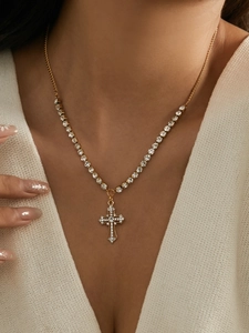 Close-up of gold-plated cross necklace with white rhinestones on model's neck
