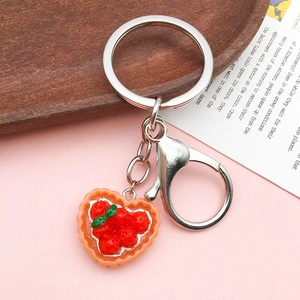 Detail of a handmade heart-shaped strawberry tart resin charm with silver keychain