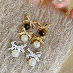 Detailed shot of 18K gold plated bow earrings with sparkling zircons and pearls