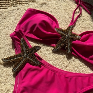 Macro shot of rose pink bikini with luxury sequined starfish beads on plush background