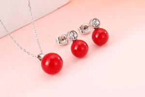 Detailed view of jewelry set with red bead pendants and cubic zirconia in silver finish