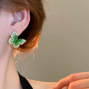 Close-up of 18k gold butterfly earring with green stone and pavé cubic zirconia