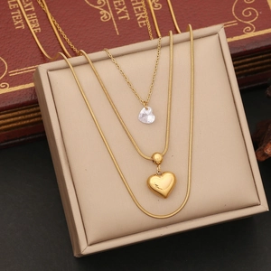 Detail of layered gold necklaces with crystal heart pendant on a beige display box