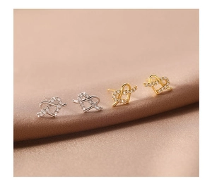 Macro detail of heart knot stud earrings in gold and silver with shimmering pavé zircon