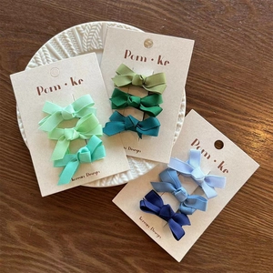 Flat lay of rainbow bow hair clips in blue and green shades on a wooden table