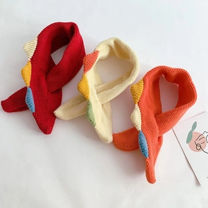 Detailed flat lay of knitted baby scarves in red, beige, and orange with geometric patterns