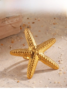 Macro shot of large golden starfish ring with grainy relief texture on beach sand