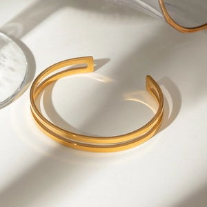 Detail of 18k gold plated stainless steel hollow double layer bangle on white background