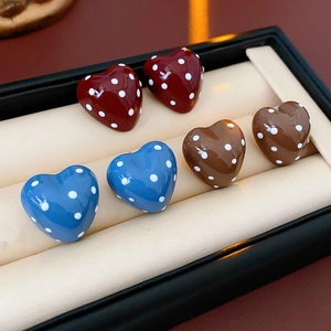 Detailed view of heart-shaped polka dot earrings in red, brown, and blue in a jewelry box