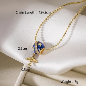 Macro shot of 18K gold plated airplane and globe pendant showing dimensions and size detail