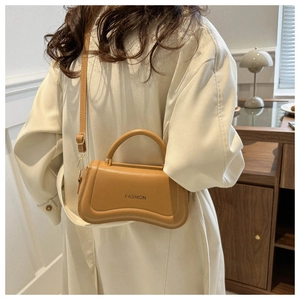 Detail of the unique wavy bottom design and fashion lettering on this camel handbag