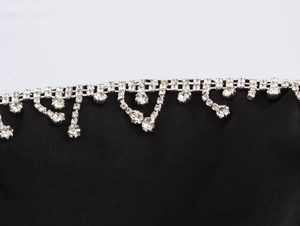 Dettaglio di strass argentati scintillanti su un elegante tessuto di raso nero