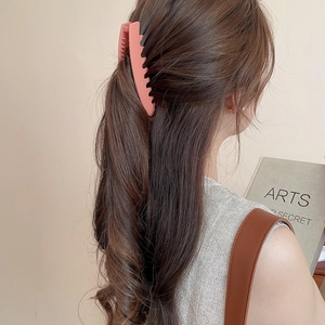 Vue latérale d'une grande pince à cheveux en acrylique rose corail mat sur demi-queue