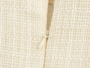 Gros plan sur la texture du tweed beige avec détail d'une fermeture éclair invisible