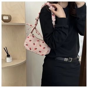 Detail of pink corduroy shoulder bag with strawberry print and scrunchie strap
